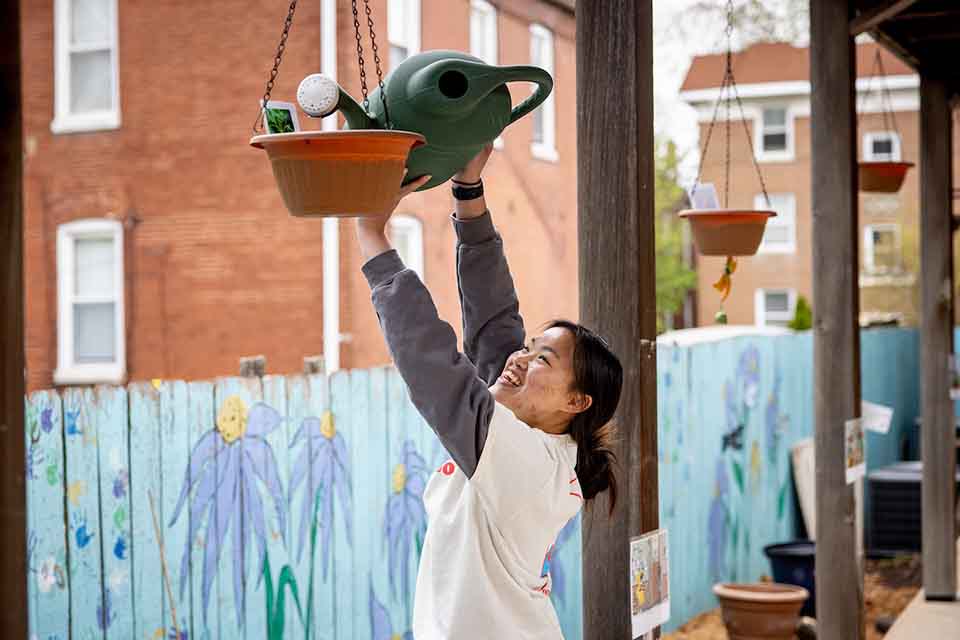 SLU student volunteer watering a plant on a porch